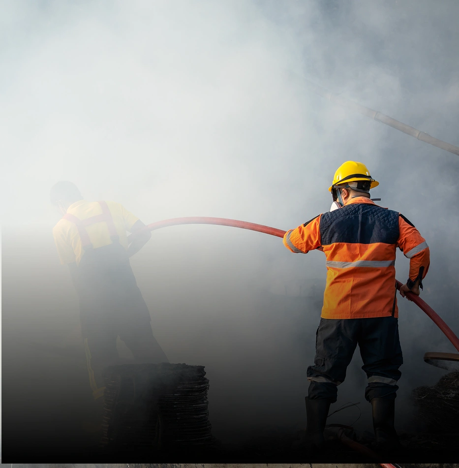 Firefighter spraying water from hose during emergency response, highlighting fire safety measures. 