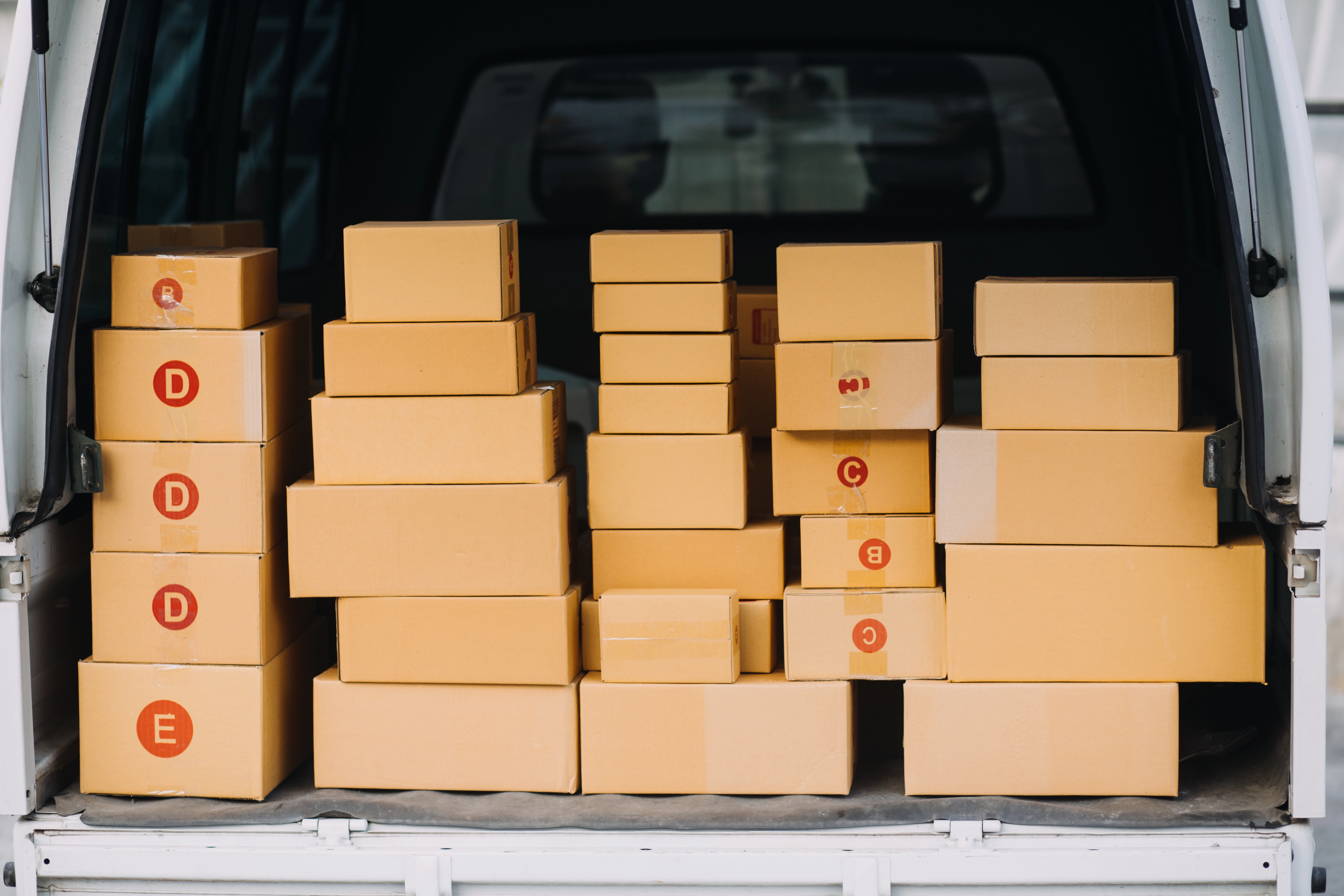 Stacked packages ready for shipping in the back of a delivery van.