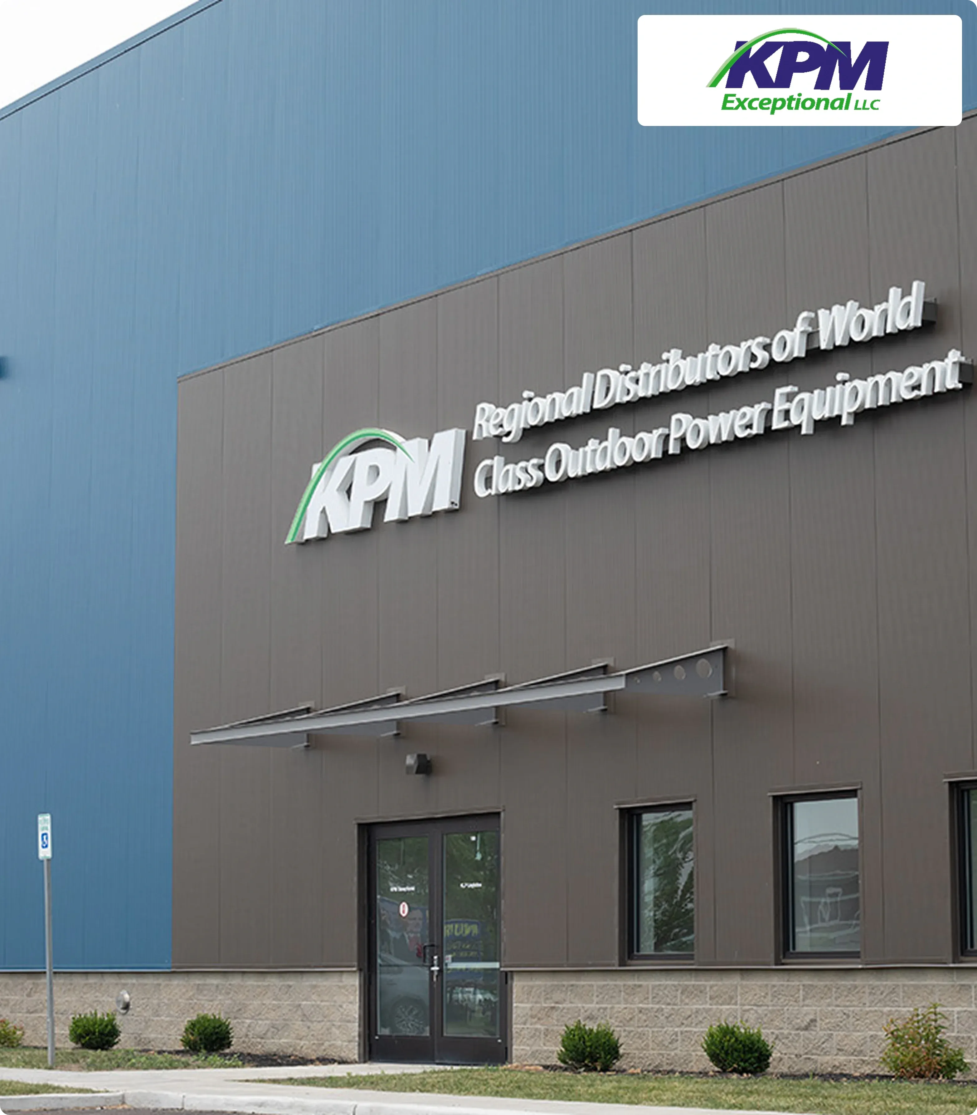 Exterior of a modern building with a logo KPM and slogan Regional Distributors of World Class Outdoor Power Equipment. Blue and gray color scheme.