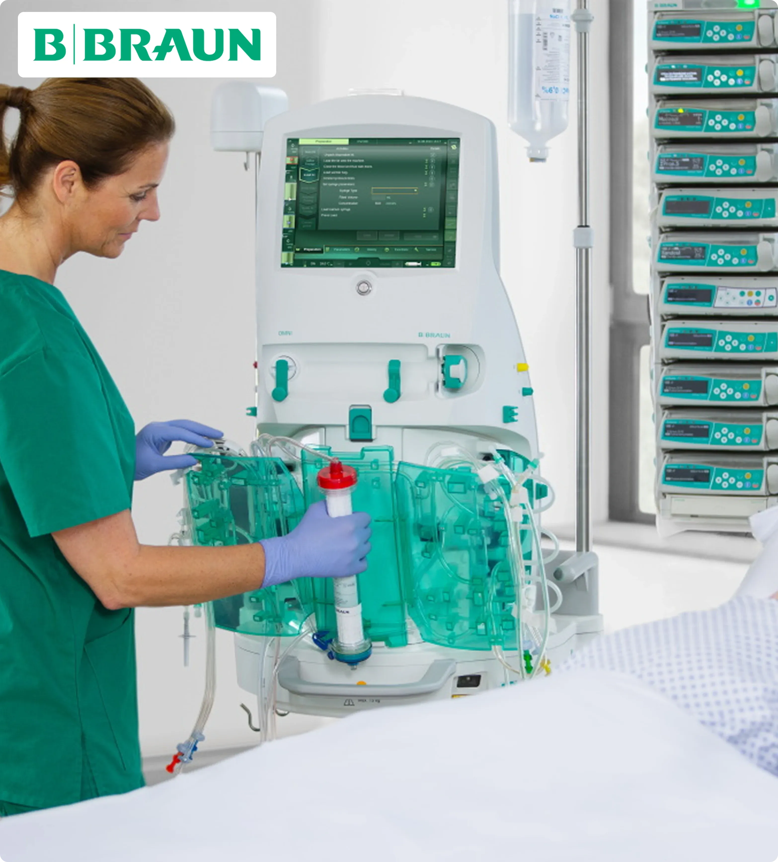 A healthcare professional in green scrubs adjusts a medical device, likely a dialysis machine, in a clinical setting. The atmosphere is sterile and focused.