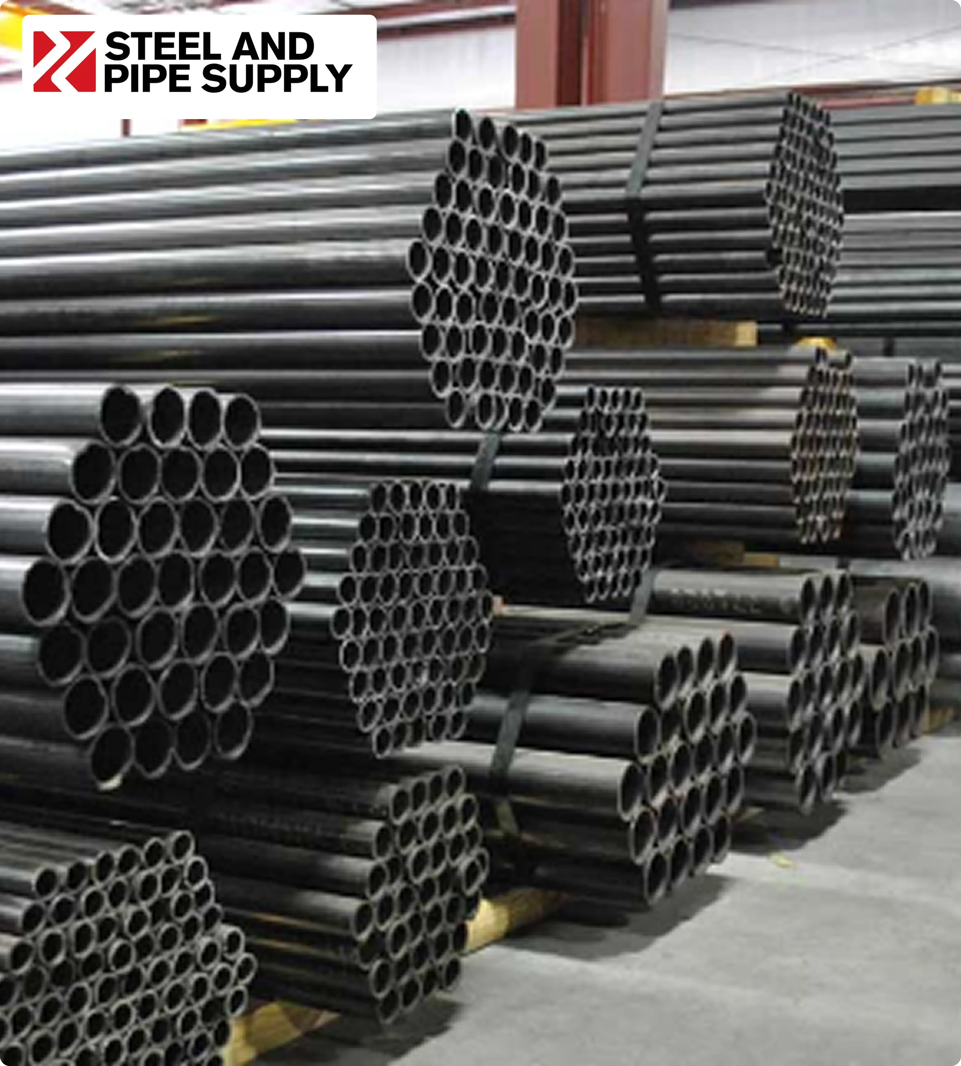 A close-up view of stacked steel pipes with green ends, forming a hexagonal shape. The Steel and Pipe Supply logo is in the upper left corner.